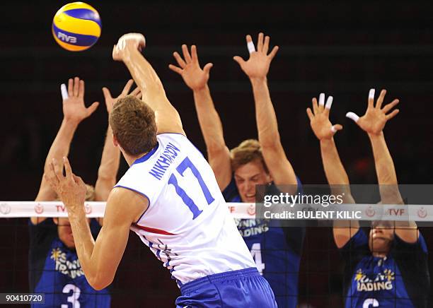 Maxim Mikhaylov of Russia spikes the ball over the net blocked by Finland`s Mikko Esko, Pekka Olli Ojansivu and Toumas Sammelvou during their...