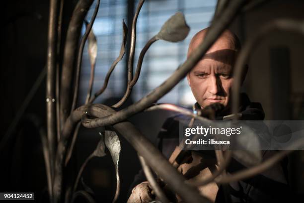 blacksmith artist working in his smithy studio creating a gate-tree - art smith stock pictures, royalty-free photos & images