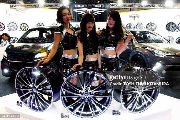 Models pose with Dorfren wheels at the company's booth of the Tokyo Auto Salon at the Makuhari Messe in Chiba on January 12, 2018. The exhibition,...