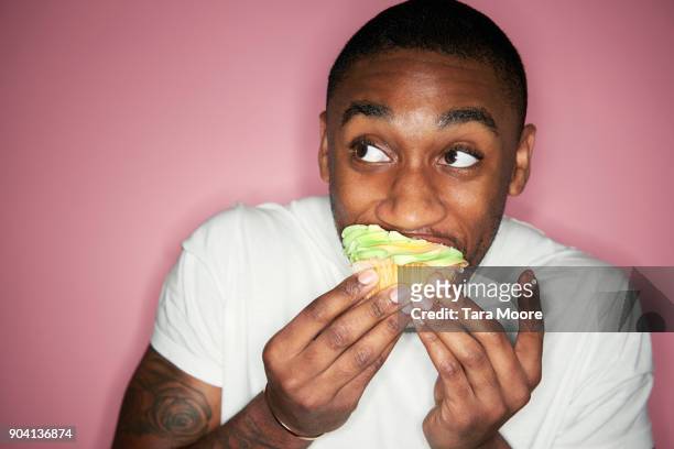 man eating cupcake - indulgence stock pictures, royalty-free photos & images