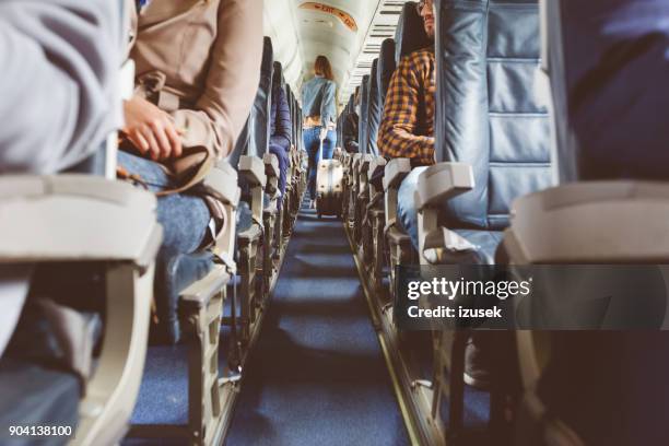 airplane interior with people sitting on seats - passenger cabin stock pictures, royalty-free photos & images