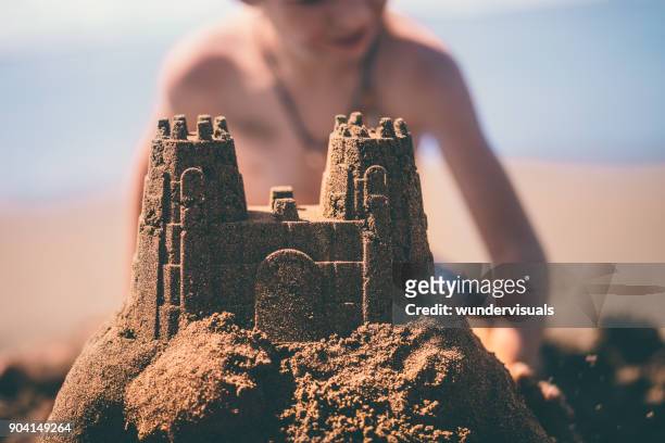 close-up of sandcastle built by boy on summer holidays - sand castle stock pictures, royalty-free photos & images