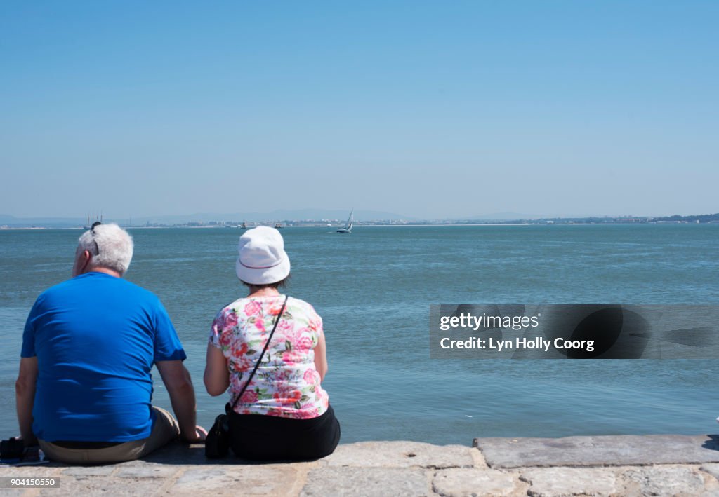 A senior couple looking out over the Tagus River Lisbon .