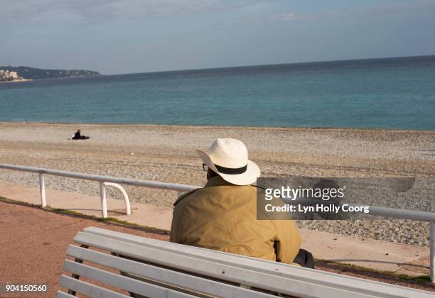 single senior man on bench by the sea - lyn holly coorg stock pictures, royalty-free photos & images