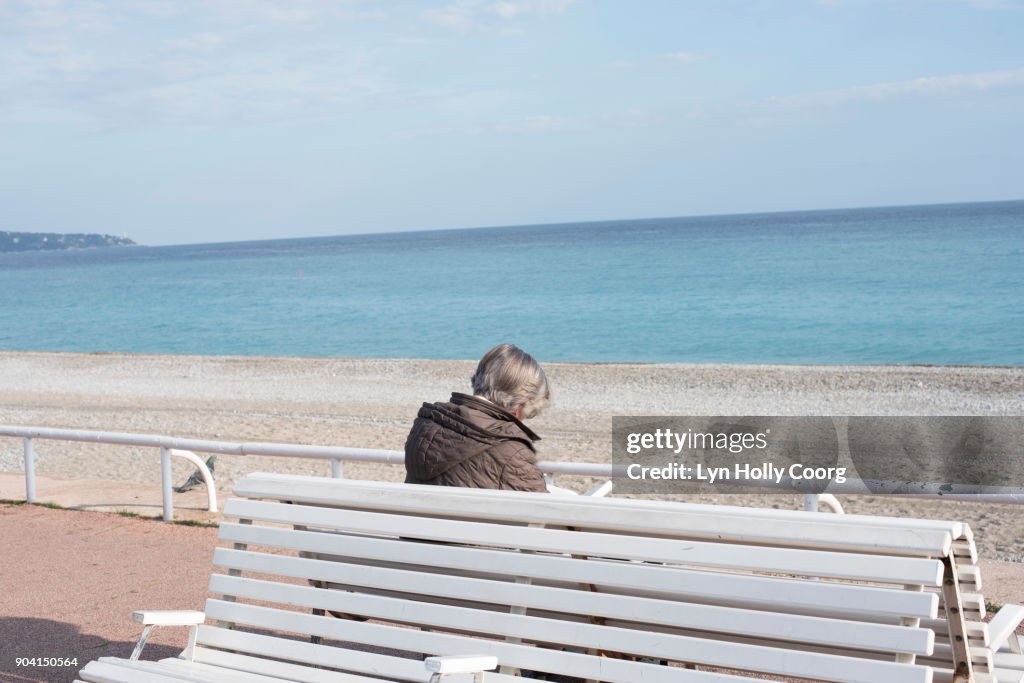 Single senior woman on bench by the sea