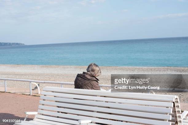 single senior woman on bench by the sea - lyn holly coorg stock pictures, royalty-free photos & images