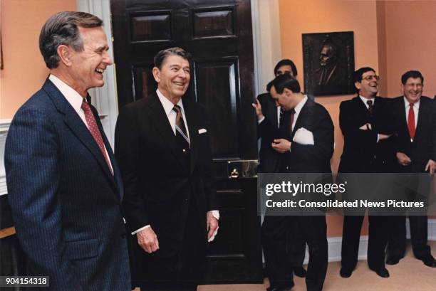 United States Vice President and President-Elect George HW Bush and outgoing President Ronald Reagan share a laugh Senior Staff members in the White...