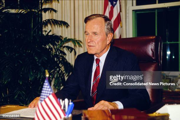 President George HW Bush sits behind his desk in the White House's Oval Office, Washington DC, October 2, 1990.
