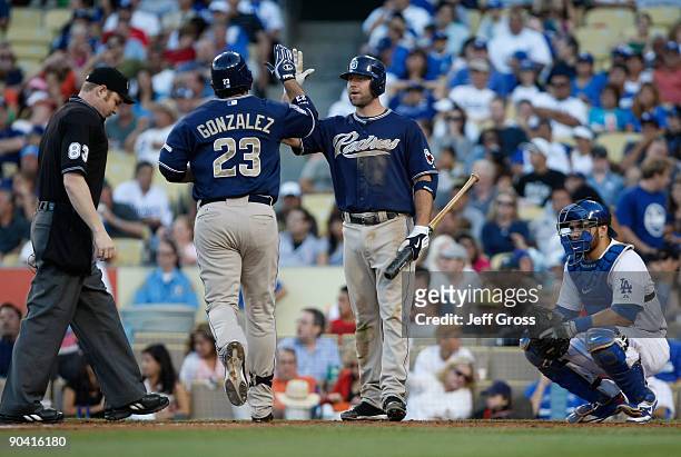 Adrian Gonzalez of the San Diego Padres receives a high five from Kevin Kouzmanoff after hitting a solo homerun in the fifth inning as catcher...