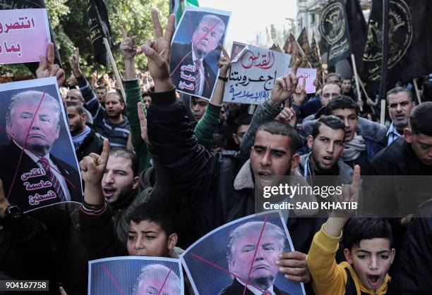 Palestinian supporters of the Islamic Jihad movement shout slogans and hold up portraits of US President Donald Trump during a protest against...