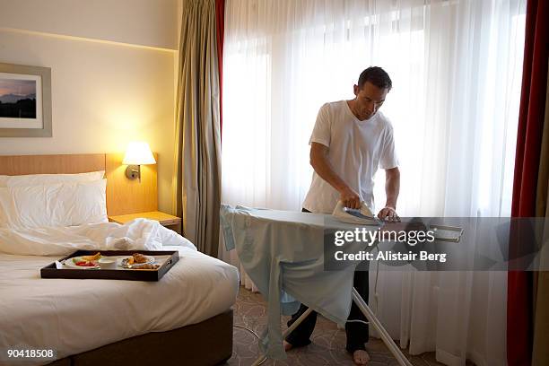 businessman ironing shirt in hotel room - businessperson breakfast stock-fotos und bilder