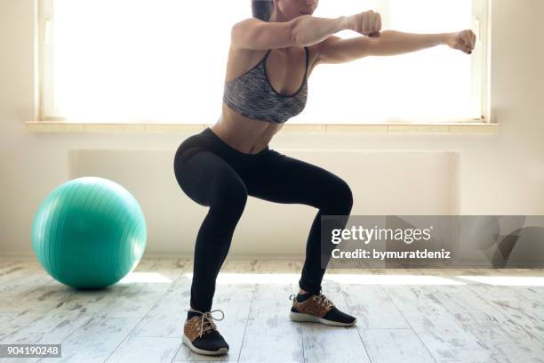 donna in abbigliamento sportivo che fa squat - glutei foto e immagini stock