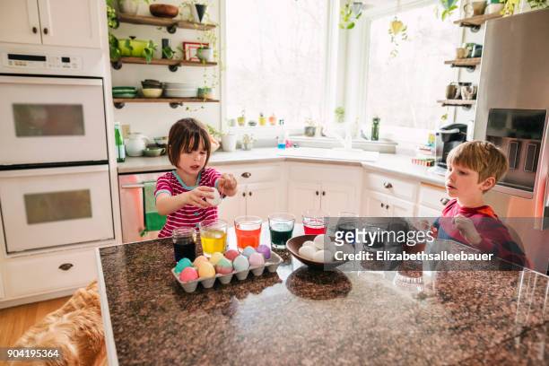 two children standing in kitchen dying easter eggs - dip dye stock pictures, royalty-free photos & images