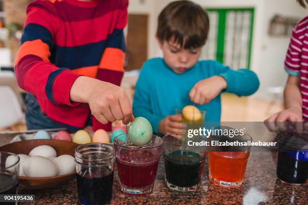 three children standing in kitchen dying easter eggs - dip dye stock pictures, royalty-free photos & images