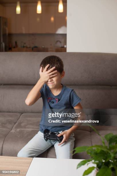 boy sitting on couch playing video games - losing virginity stock-fotos und bilder