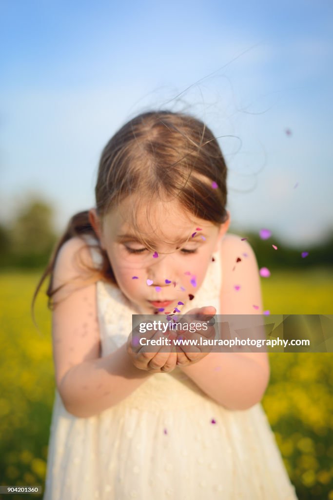 Young girl blowing glitter in buttercup field