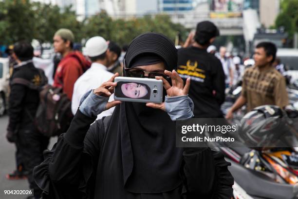 Woman with her profile picture at the back of the smartphone took picture of the demonstration banner. Hundreds of muslims from Indonesian Islam...