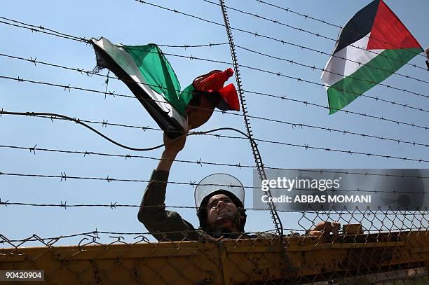 An Israeli soldier removes a Palestinian flag hung on the barbed wire around the gate of the Israeli-controlled Ofer jail during a protest calling...