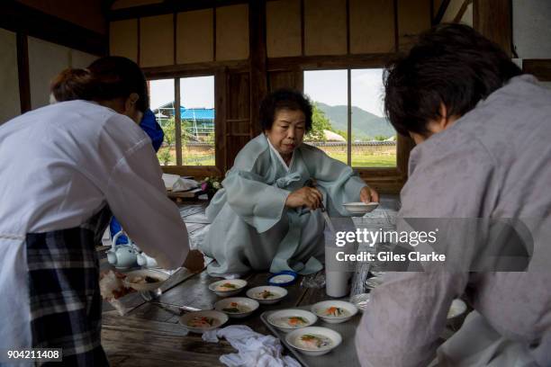 Women dressed in traditional Korean clothing prepare a lunch at Andong Hahoe Village. The Hahoe Folk Village is a traditional village from the Joseon...