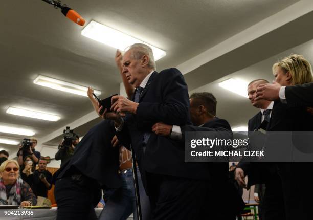 Czech President Milos Zeman is escorted by security staff as he is attacked by a woman being member of the Femen organisation on January 12, 2018 at...