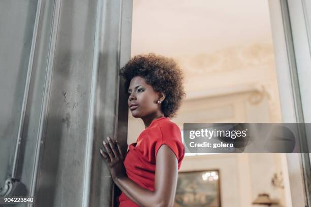 pensive beautiful young cuban woman leaning at door - havana door stock pictures, royalty-free photos & images