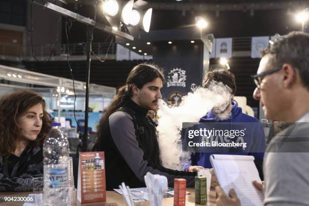 Visitor exhales vapor while testing an electronic e-cigarette device at the 1st International Cannabis Expo at the Faliro Sports Pavilion in Athens,...