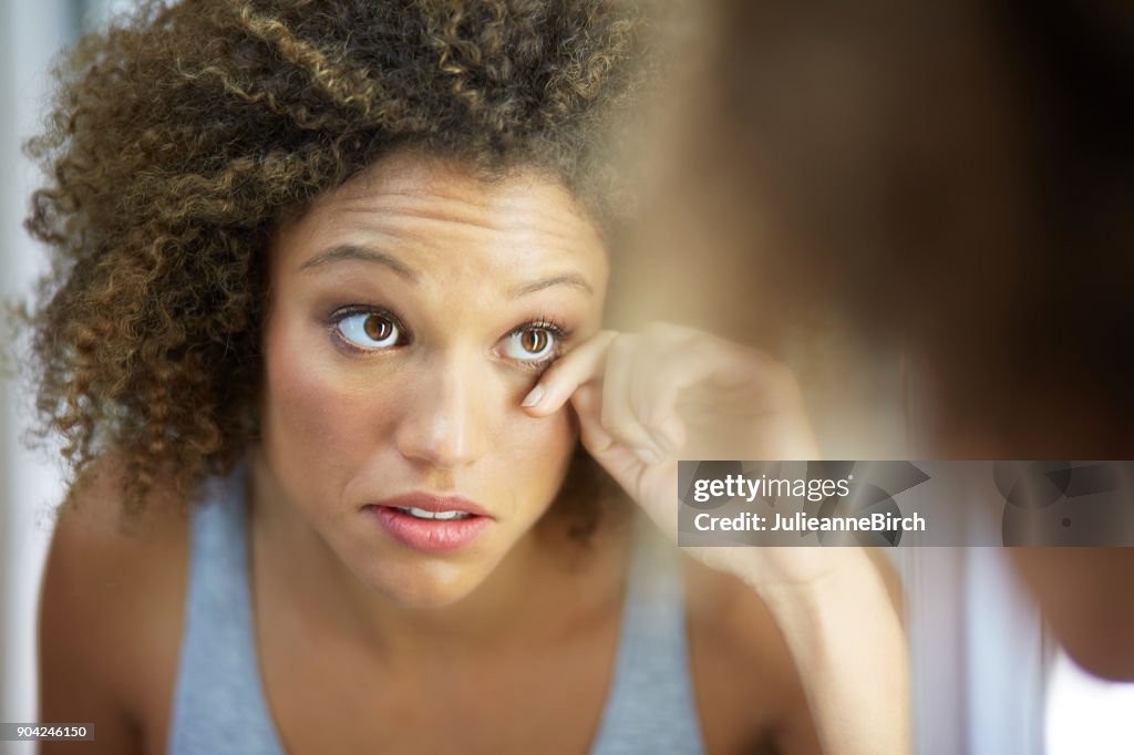 Pretty young woman in mirror checking make up