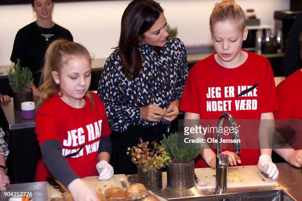 Crown Princess Mary of Denmark speaks to young kids preparing food during her visits to the Christmas Seal Foundation home opening on January 12,...
