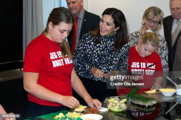 Crown Princess Mary of Denmark speaks to young kids preparing food during her visits to the Christmas Seal Foundation home opening on January 12,...