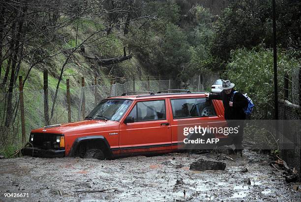 Man walks past a vehicle stuck in the mud of a landslide, following heavy rains in Santiago on September 7, 2009. A landslide in the mountainous area...