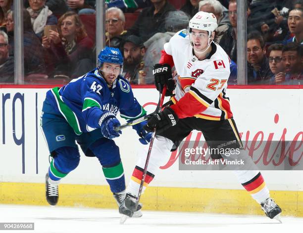 Alexander Burmistrov of the Vancouver Canucks checks Sean Monahan of the Calgary Flames during their NHL game at Rogers Arena December 17, 2017 in...