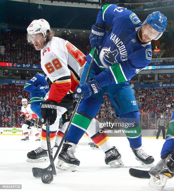 Jaromir Jagr of the Calgary Flames and Alexander Burmistrov of the Vancouver Canucks battle for the puck during their NHL game at Rogers Arena...