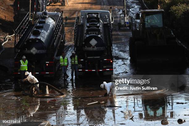 Workers attempt to drain a section of Highway 101 that was flooded following a mudslide on January 12, 2018 in Montecito, California. 17 people have...