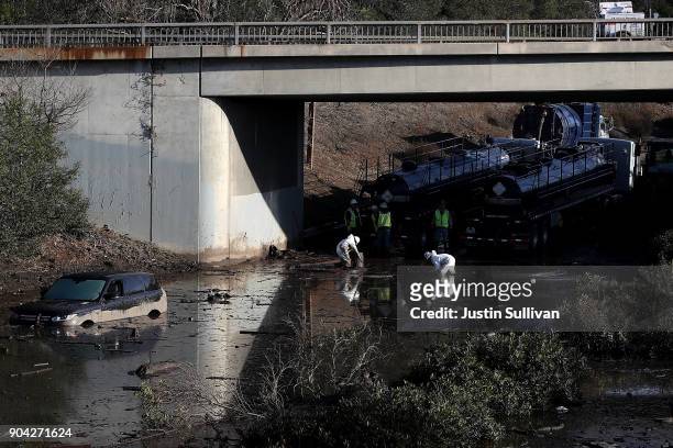 Workers attempt to drain a section of Highway 101 that was flooded following a mudslide on January 12, 2018 in Montecito, California. 17 people have...