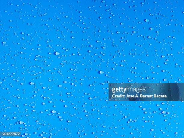 full frame of the textures formed by the bubbles and drops of water, on a smooth  blue background. - rain drop stock pictures, royalty-free photos & images