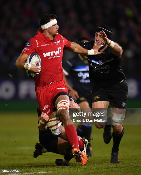 Aaron Shingler of Scarlets is tackled by Chris Cook and Luke Charteris of Bath during the European Rugby Champions Cup match between Bath Rugby and...