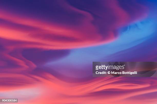 moody lenticular clouds at sunset - imponente fotografías e imágenes de stock
