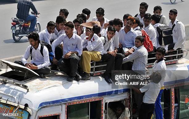 Pakistani students sit on top of an overloaded mini bus as they ride home from school in Lahore on September 8, 2009. Pakistan�s Prime Minister...