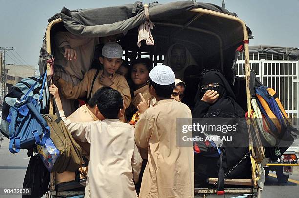 Pakistani students hold onto an overloaded van as they ride home from school in Lahore on September 8, 2009. Pakistan�s Prime Minister Yousuf Raza...