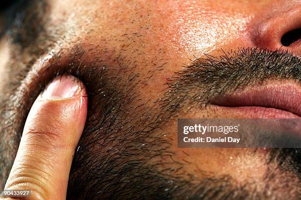 man pressing finger against cheek - barba por fazer imagens e fotografias de stock