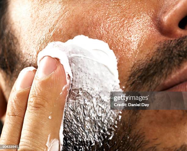 man applying cream to face - barba incolta foto e immagini stock