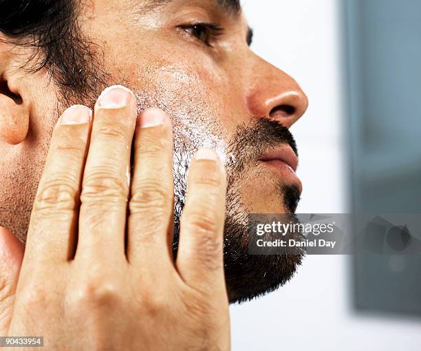 man applying cream to face - hair stubble stock-fotos und bilder