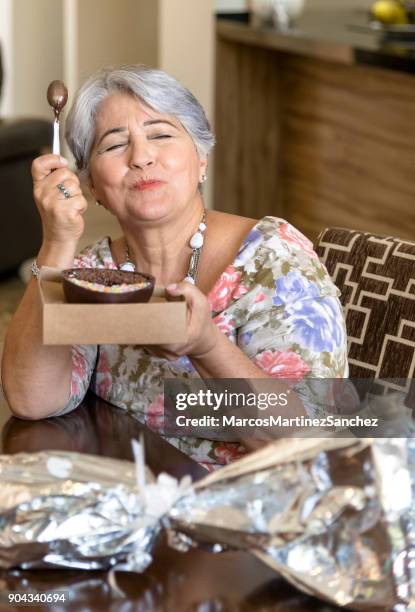 easter celebration - grandmother tasting chocolate eggs - lypsesp17 stock pictures, royalty-free photos & images