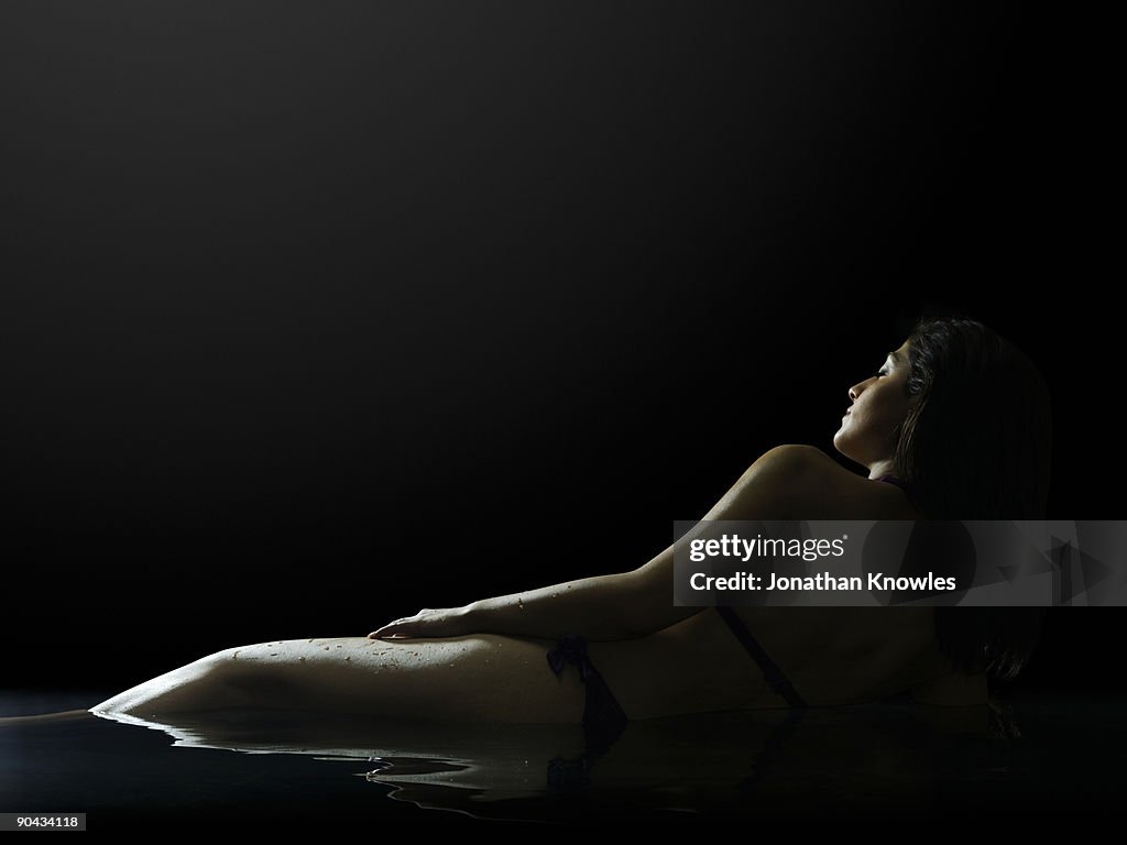 Woman lying in water bathed in moonlight