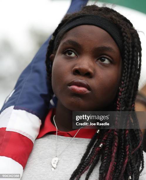 Erika Rigaud holds an American flag as she joins with others to mark the 8th anniversary of the massive earthquake in Haiti and to condemn President...