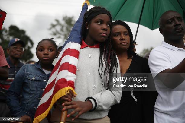 Erika Rigaud holds an American flag as she joins with others to mark the 8th anniversary of the massive earthquake in Haiti and to condemn President...