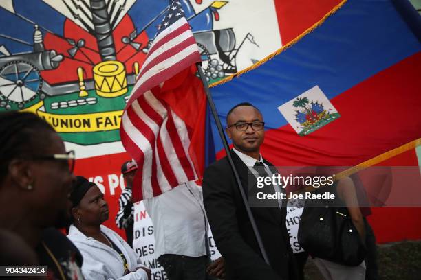 Fandzy Bernadin holds an American flag as he joins with others to mark the 8th anniversary of the massive earthquake in Haiti and to condemn...