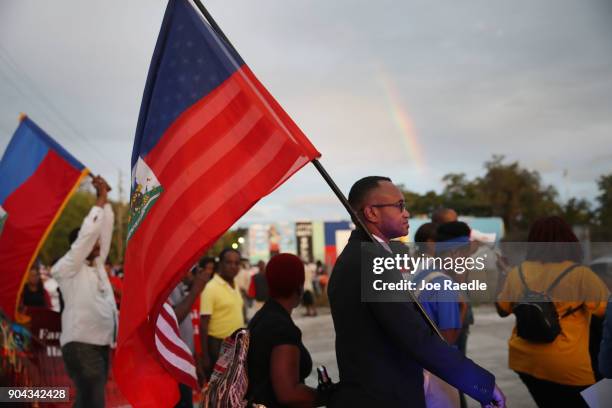 Fandzy Bernadin carries a Haitian and an American flag as he joins with others to mark the 8th anniversary of the massive earthquake in Haiti and to...