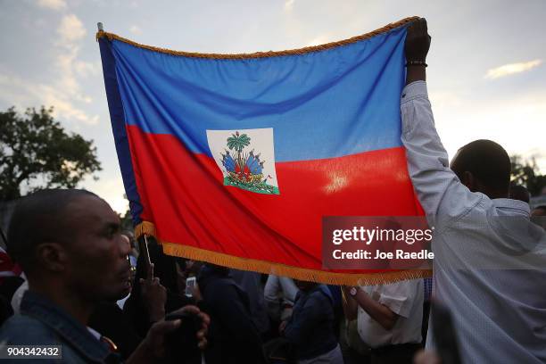 People hold a Haitian flag as they gather together to mark the 8th anniversary of the massive earthquake in Haiti and to condemn President Donald...