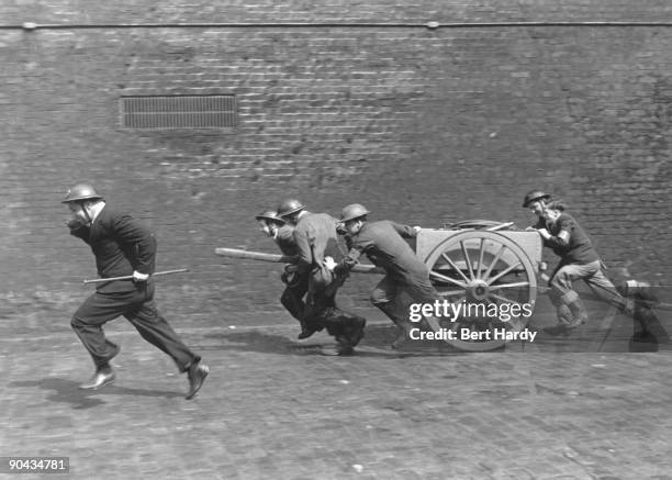 Fire squad rushes along a dock wall in the East End of London to the scene of a fire after an air raid during the Blitz, April 1941. The group are...